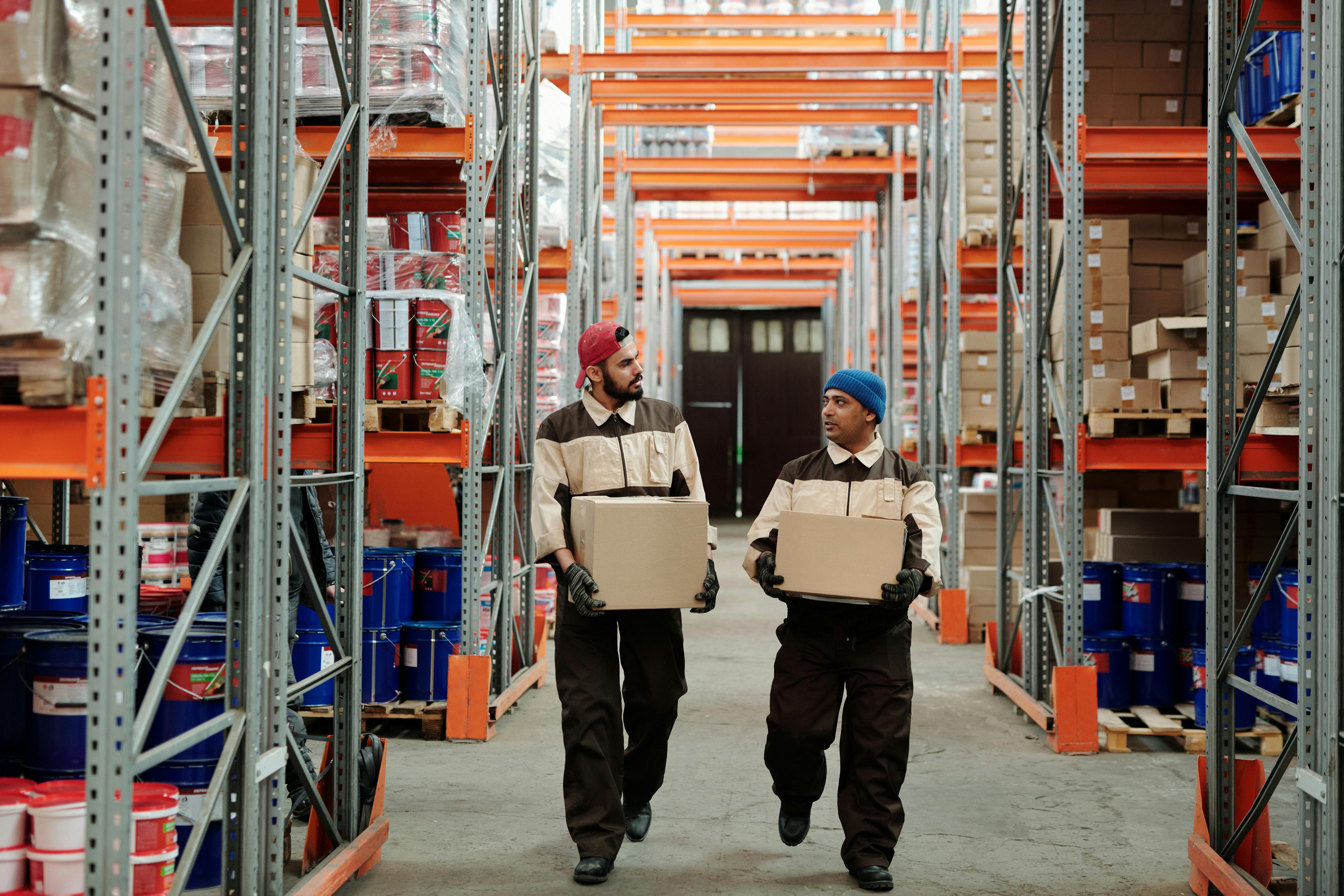 two men working in a warehouse, each holding a box